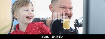 Ridendo la ragazza e l'uomo cantano la canzone nel closeup del microfono Foto Stock