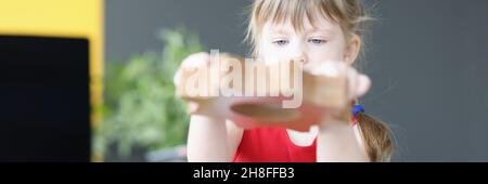 La bambina piega gli ingranaggi di legno sul tavolo Foto Stock