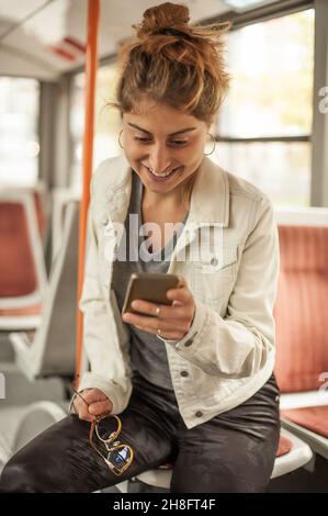 La ragazza giovane usa un telefono cellulare nel bus della città. Tecnologia di isolamento del telefono cellulare. Internet e social media Foto Stock