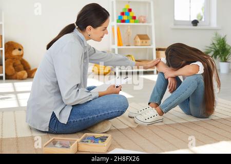 Specialista cercando di aiutare triste, bambino stressato per risolvere i problemi di comportamento e di apprendimento Foto Stock