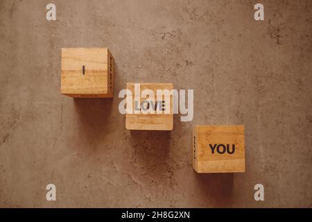 Vi amo più lettere timbro su blocchi di legno sul vecchio sfondo di cemento Foto Stock