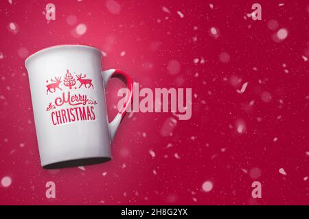 Allegra tazza di Natale con sfondo rosso nevoso e spazio per la copia. Design di concetto di Natale. Foto Stock