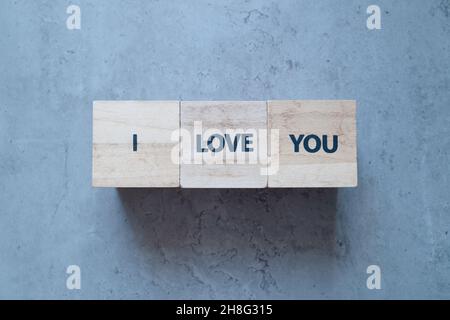 Vi amo più timbro lettere testo su blocchi di legno sul vecchio sfondo concreto Foto Stock