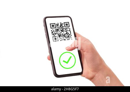 La mano della donna tiene un telefono con un certificato di vaccinazione su sfondo bianco. Codice QR e segno di spunta verde nello smartphone. Foto Stock