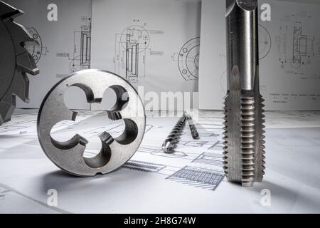 Primo piano di una scrivania di design piena di punte da trapano, cuscinetti e diagrammi meccanici. Foto Stock
