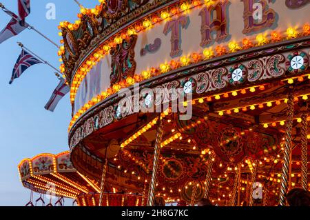 Classic Carousel, Merry Go Round, al Goodwood Revival vintage event 2014, al crepuscolo con luci. Giro di divertimento alla rotatoria Foto Stock