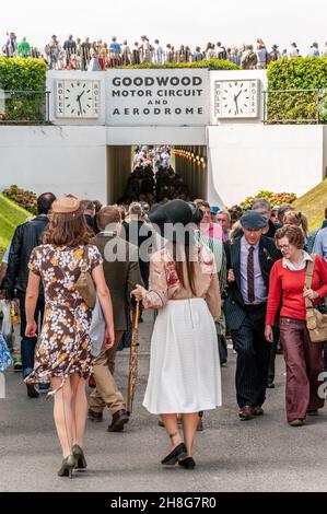 Visitatori in costumi d'epoca al Goodwood Revival utilizzando il tunnel pedonale sotto il circuito automobilistico. Persone in abbigliamento vintage. Femmine in costume Foto Stock