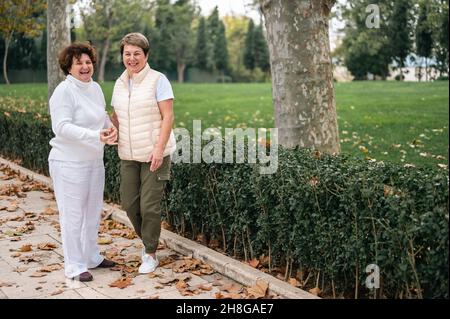 due donne anziane ridono e guardano la macchina fotografica. due vecchi amici si sono incontrati nel parco. stile di vita attivo di donne anziane e di mezza età. amici anziani ar Foto Stock