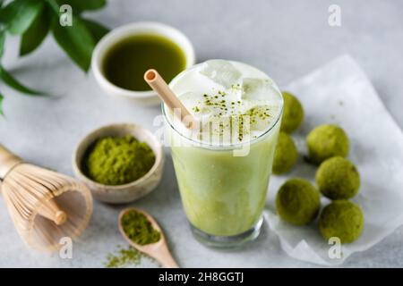 Tè Matcha al latte di ghiaccio in vetro servito con palle di energia cruda. Cibo vegano Foto Stock