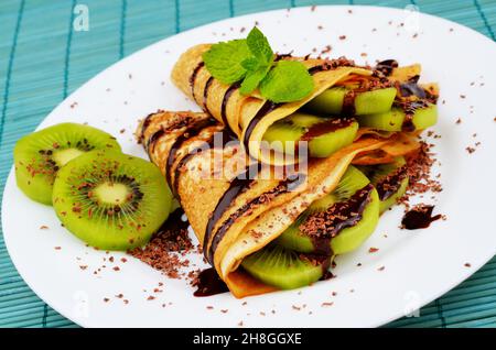 Stile Francese crepes con kiwi, salsa al cioccolato e trucioli Foto Stock