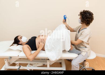 Ginecologo in possesso di un apparato muscolo pelvico del pavimento esercizio per preparare per la nascita di una donna sdraiata Foto Stock