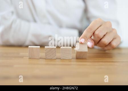 Donna di affari che capovolgono un cubo di legno dalla fila Foto Stock