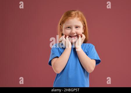 Ritratto di simpatica ragazza rossa emotiva su sfondo rosso Foto Stock