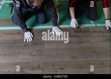 Un lavoratore bussa a mano su un laminato che collega i pannelli con un clic di blocco Foto Stock