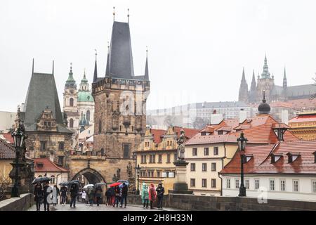 Praga - 11 marzo 2020: Ponte Carlo e Castello di Praga. Le persone con ombrelloni camminano sotto la pioggia sul Ponte Carlo Foto Stock