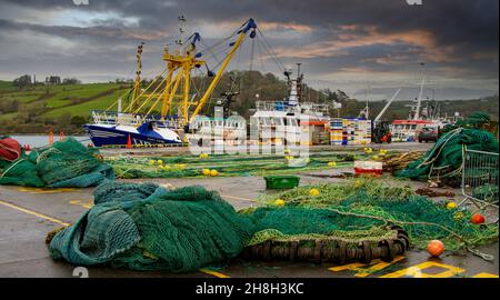 Beam Trawler ormeggiato sotto cieli tempestosi con reti da pesca su un molo. Foto Stock