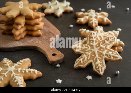 Decorazioni natalizie di Capodanno, biscotti al pan di zenzero, tagliere, candele, stelle dello zucchero e palle su una superficie scura. Messa a fuoco selettiva Foto Stock