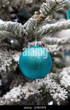 Bauble blu acqua con glitter appeso a un albero di Natale gelido Foto Stock