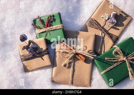 Avvolti regali di Natale con decorazione in neve. Posa piatta di scatole regalo in carta da imballaggio verde e marrone kraft Foto Stock