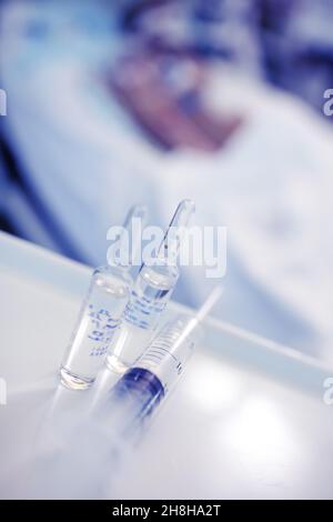 Flaconcini di farmaco e siringa al posto letto del paziente in ospedale. Foto Stock