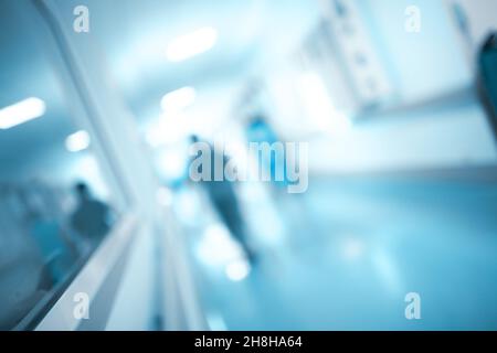 Figura oscura che cammina attraverso il corridoio dell'ospedale, sfondo sfocato. Foto Stock