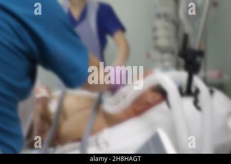 Personale medico che si prende cura di pazienti gravemente malati in terapia intensiva, background non focalizzato. Foto Stock