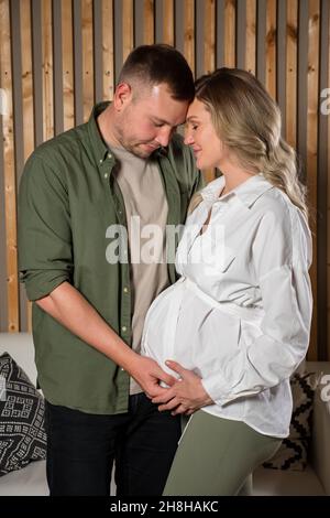 La coppia felice guarda teneramente al ventre della donna incinta Foto Stock