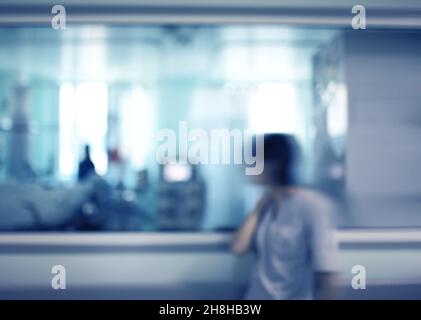 Infermiera femminile che guarda attraverso la finestra di osservazione del reparto ospedaliero, sfondo non focalizzato. Foto Stock