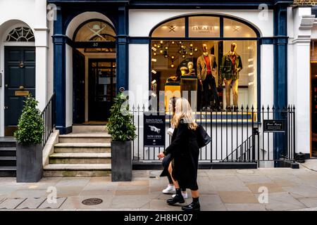 Due giovani Donne camminano accanto al negozio di abbigliamento Hackett Mens, King Street, Covent Garden, Londra, Regno Unito. Foto Stock