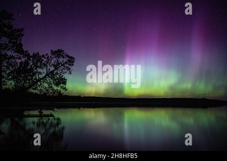L'aurora boreale riempie il cielo di colori brillanti sul lago Little Sand nel Minnesota settentrionale. Foto Stock