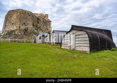 Barche ribaltate usate come capanne sotto il Castello di Lindisfarne a Holy Island sulla costa di Northumberland in Inghilterra, Regno Unito Foto Stock