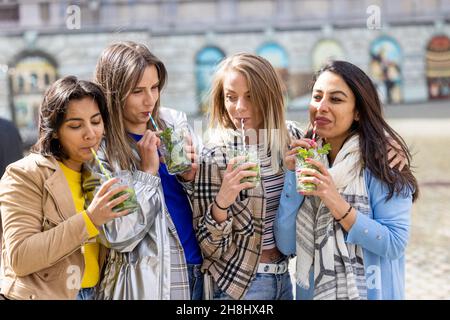 Gruppo etnico Muti di amici femminili che si divertono bevendo cocktail all'aperto in città nel bar ristorante. Foto di alta qualità Foto Stock