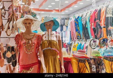 Due manichini di ragazze in abito e cappelli da sole sullo sfondo del negozio con vestiti e scarpe Foto Stock