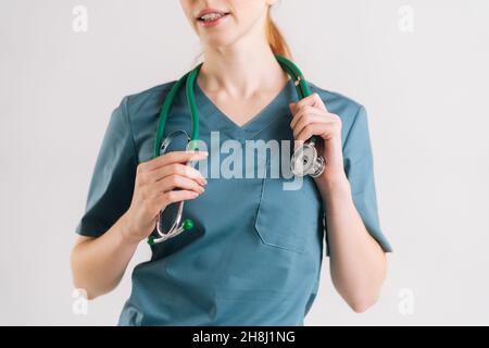 Primo piano scatto ritagliato di medico femminile irriconoscibile in uniforme medica verde con stetoscopio intorno al collo. Foto Stock