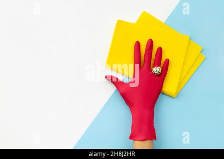 Womans mano nel panno di gomma rosa da straccio sopra sfondo blu Foto Stock