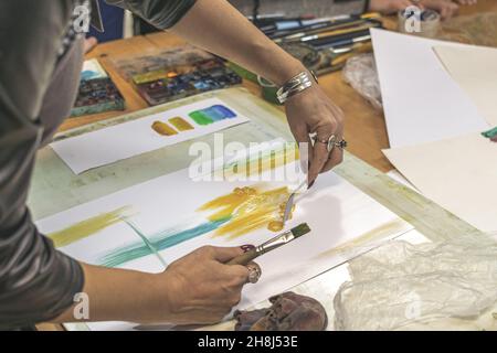 L'artista dipinge i disegni acquerelli su carta con il coltello della tavolozza. Masterclass di pittura ad acquerello Foto Stock