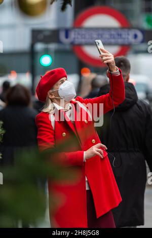 Londra, Regno Unito. 30 novembre 2021. Una donna al di fuori degli alberi di Natale di Harvey Nichols a Knightsbridge il primo giorno in cui le coperture del viso sono nuovamente richieste nei negozi seguendo le nuove misure del governo britannico per cercare di frenare la diffusione del coronavirus in seguito al rilevamento della variante Omicron. Credit: Stephen Chung / Alamy Live News Foto Stock