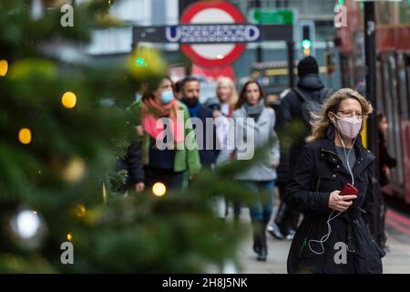 Londra, Regno Unito. 30 novembre 2021. La gente passa gli alberi di Natale fuori da Harvey Nichols a Knightsbridge il primo giorno in cui le coperture di faccia sono di nuovo richieste nei negozi seguendo le nuove misure del governo britannico per cercare di frenare la diffusione del coronavirus dopo il rilevamento della variante di Omicron. Credit: Stephen Chung / Alamy Live News Foto Stock