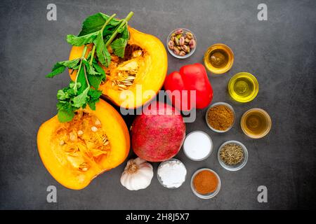 Zuppa di zucca arrosto marocchina ingredienti su sfondo scuro: Zucca, melograno, peperone rosso, erbe e spezie mostrate dall'alto Foto Stock