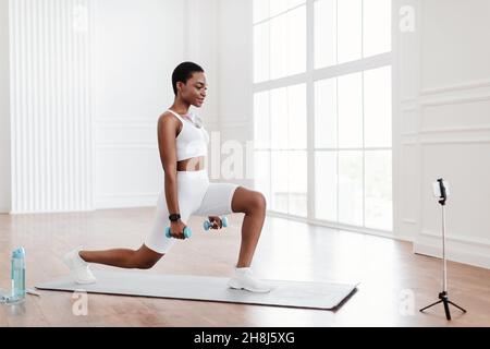 La donna nera che fa avanti affondi davanti al cellulare Foto Stock