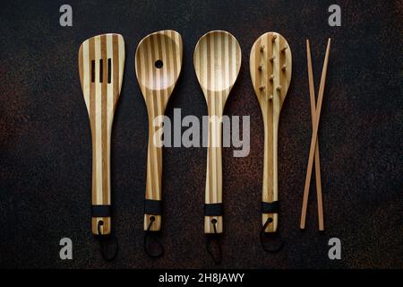 Utensili di cucina in legno di bambù su sfondo scuro primo piano Foto Stock