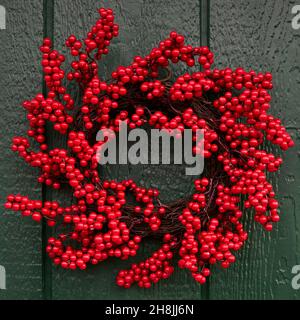 Una festa di Natale decorativo winterberry wreath su una porta fienile verde Foto Stock