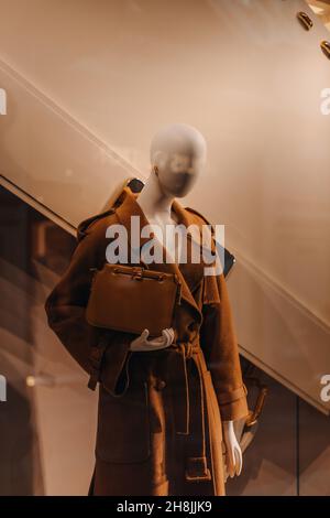 Un manichino vestito con un elegante cappotto marrone lungo e con una borsa in pelle femminile nelle mani. Collezione moda autunno inverno Foto Stock