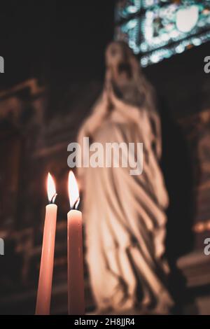 Candele accese nella chiesa con l'altare e icone cristiane sullo sfondo. Religione cattolica romana. Concetto religioso Foto Stock