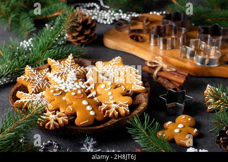 Biscotti fatti in casa di pan di zenzero sotto forma di favolosi uomini di pan di zenzero, fiocchi di neve e alberi di natale su piatto di legno in composizione anno nuovo così come m Foto Stock