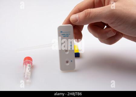 shot isolato di una mano destra contenente un campione in bianco per test pandemico dell'antigene coronavirus covid-19 con una lancetta e soluzione su una ba bianca Foto Stock