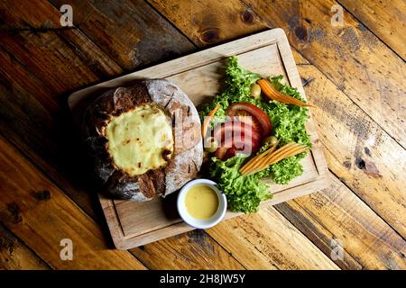 pane di contadino ripieno di carne e pollo coperto di formaggio con insalata Foto Stock