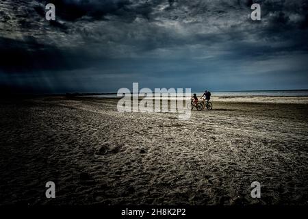 padre e figlio stanno pedalando sulla spiaggia Foto Stock