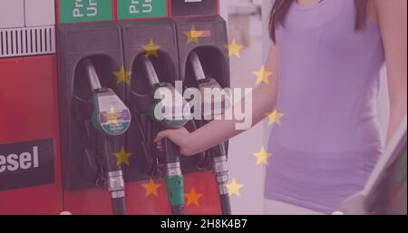 Doppia esposizione della donna che detiene la pompa di benzina presso la stazione di servizio con bandiera dell'Unione europea Foto Stock