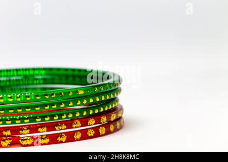 Primo piano di braccialetti di vetro rosso e verde (bracciali) con punti dorati su sfondo bianco Foto Stock